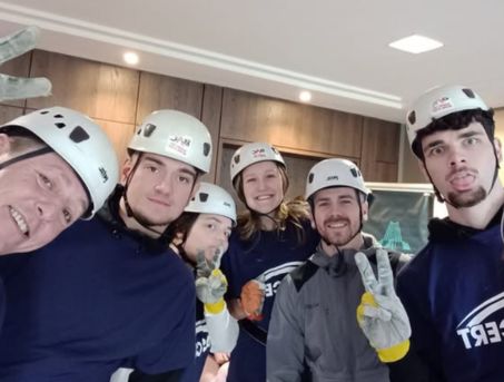 A group of volunteers wearing ASCERT t-shirts and white helmets pose for the camera before their abseil.