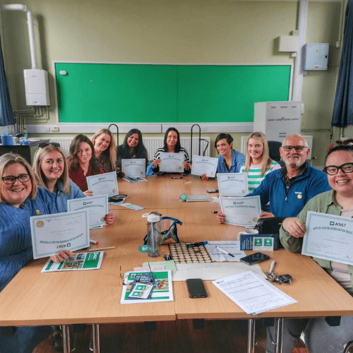 A group of ASCERT employees sit around a table with a certificate of completion for their CPD training.