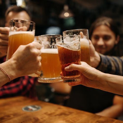 A group of people clink their pints of beer.
