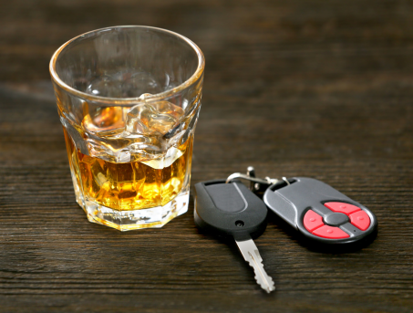 A glass of whiskey with car keys next to it.